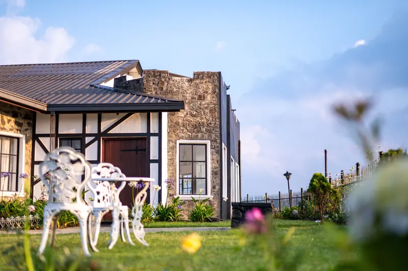 The stone front of the cottage with garden chairs on the lawn