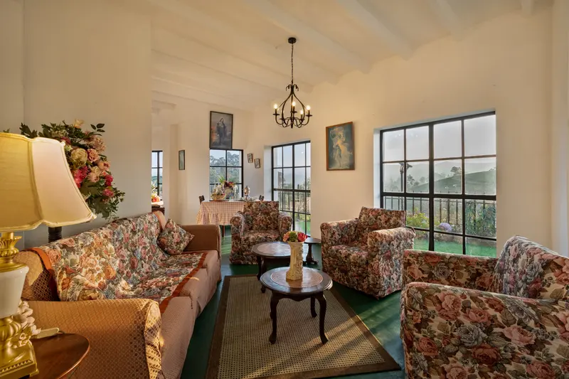 The sitting room: floral armchairs, a chandelier and tall windows onto the tea estate