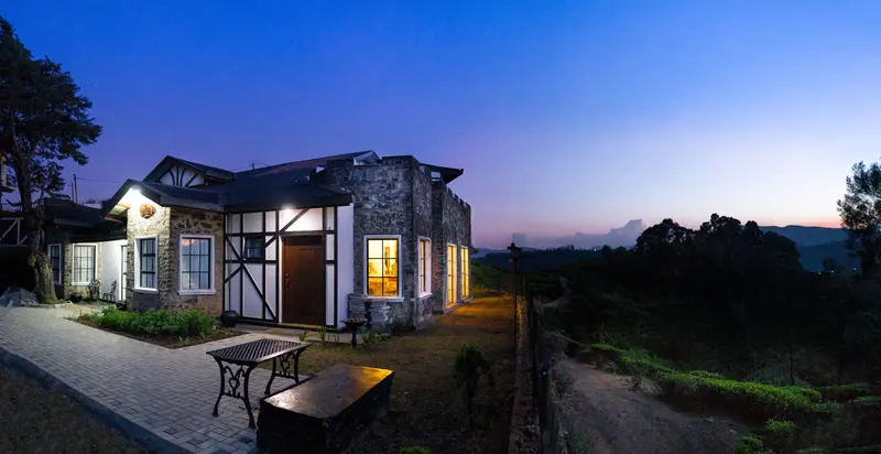 Dover Cottage lit at dusk, with the tea fields fading into the dark