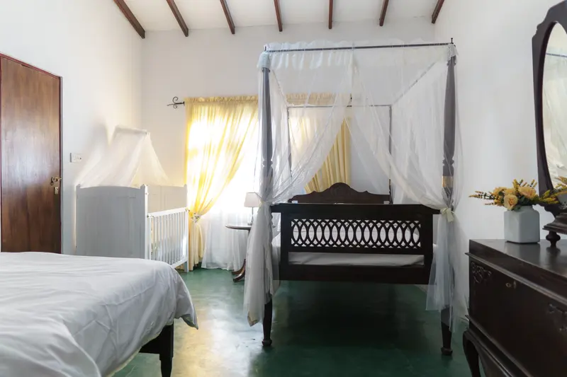 Daffodil bedroom: a four-poster double under a white canopy, with a single bed alongside