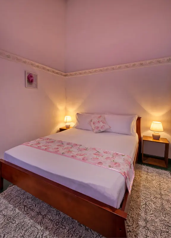 Rose bedroom: a double bed with a rose-print runner and pink walls