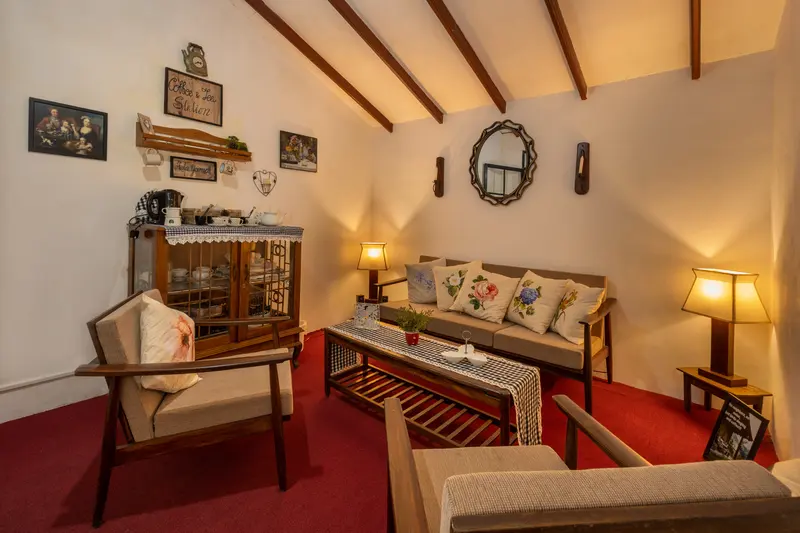 The tea station: a glass-fronted cabinet of cups beside armchairs on a red floor